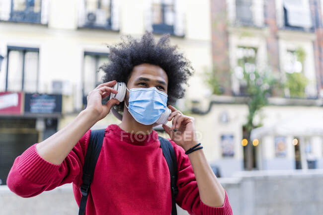 Young man with afro hair listening to music from his smartphone — Stock Photo