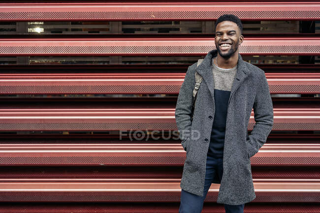 Retrato de un hombre de negocios afro en la ciudad sobre una pared roja - foto de stock
