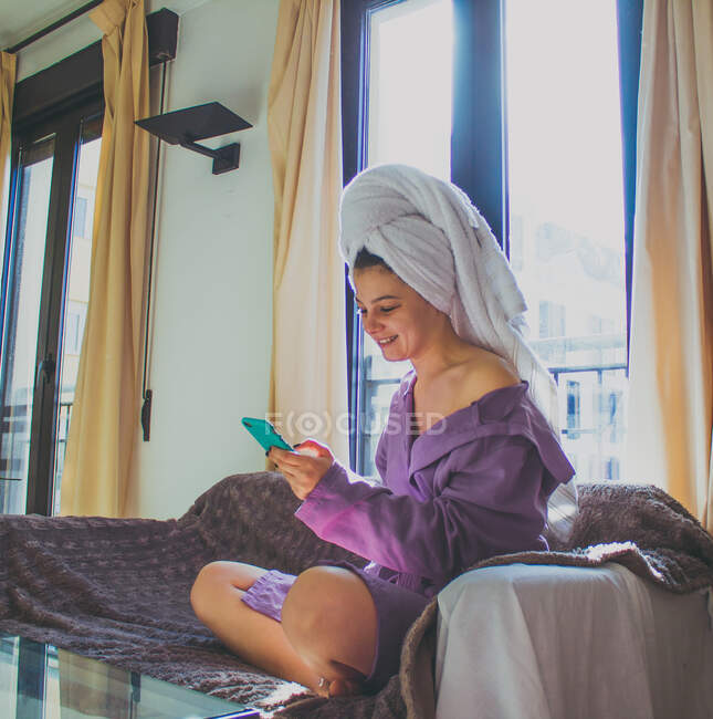 Schöne junge Frau mit Smartphone im Schlafzimmer — Stockfoto