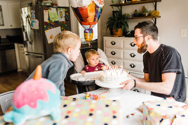 Un año de edad celebrando cumpleaños con la familia en la mesa con pastel - foto de stock