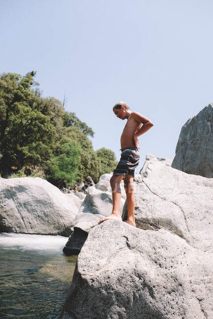 Tween Boy Contemplates Saltando de uma rocha no rio — Fotografia de Stock