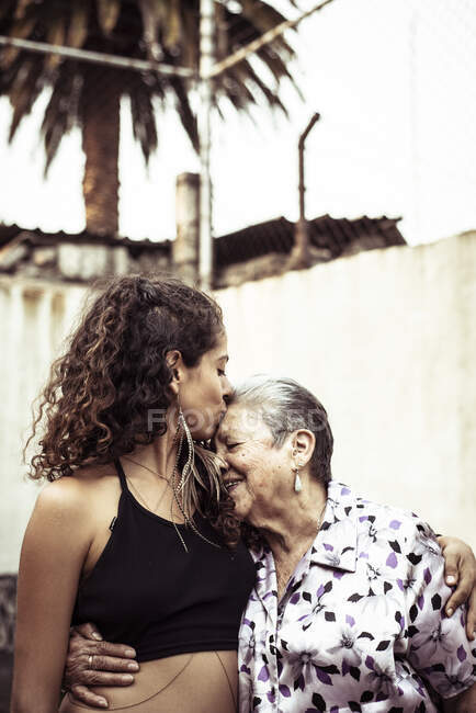Giovane donna messicana attraente bacia la nonna sulla strada estiva — Foto stock