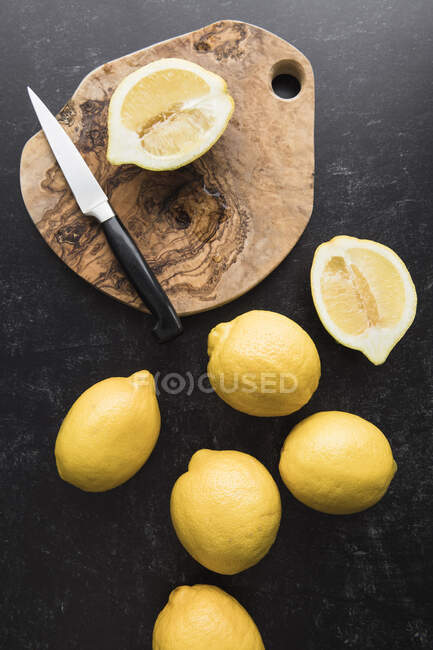 Frische Zitronenscheiben auf einem Schneidebrett auf schwarzem Hintergrund — Stockfoto