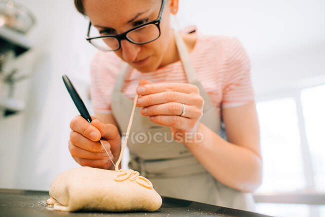 Primo piano di un panettiere donna che decora il pane al lavoro — Foto stock