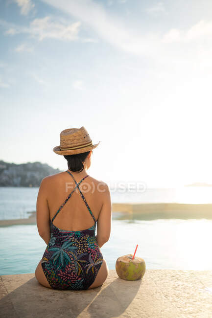 Happy woman relaxing in the swimming pool and drinking coconut water. — Stock Photo