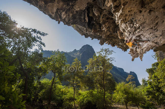 Человек, взбирающийся на известняковую скалу в Лаосе — стоковое фото