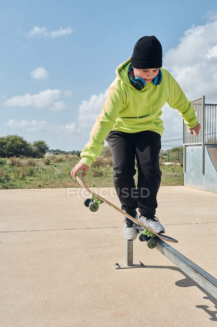 Young, teenager, with a skateboard, jumping, on a track, skateboarding, wearing headphones — Stock Photo
