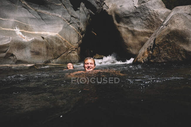 Друзья плавают вместе с камнями и кружащейся водой вокруг них — стоковое фото