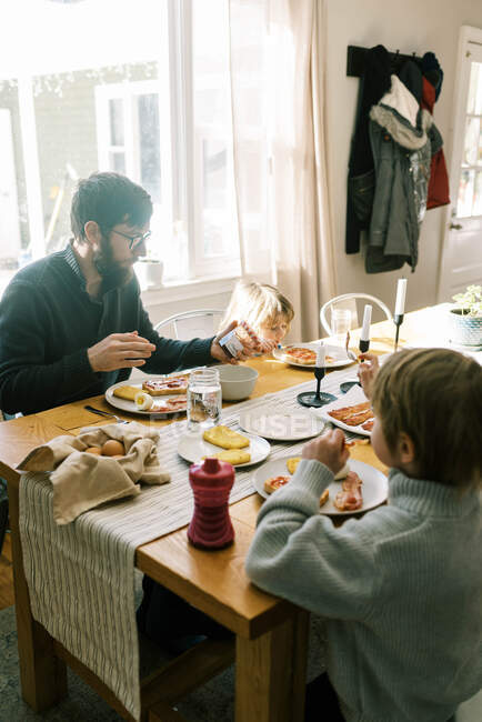 Eine Familie frühstückt gemeinsam am Esstisch in ihrem Haus — Stockfoto