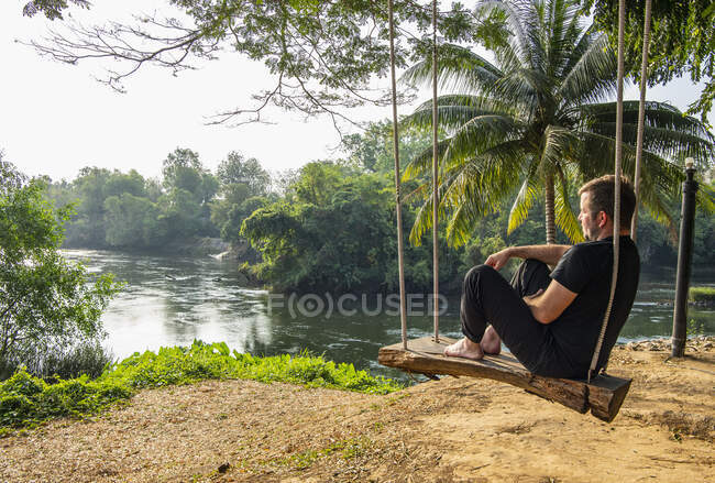 Молодой человек, сидящий у озера — стоковое фото