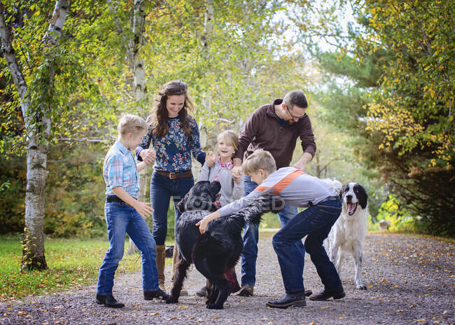 Happy family of 5 playing with two dogs on a country road. — Stock Photo