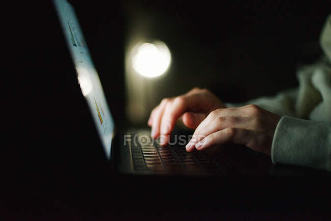 Mujer anónima trabajando en el ordenador portátil por la noche - foto de stock