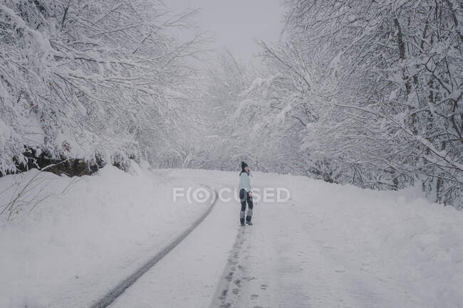 Frau läuft über verschneite Straße im Wald — Stockfoto