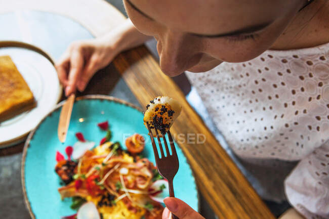 Una giovane ragazza tiene una forchetta di capesante alla bocca — Foto stock