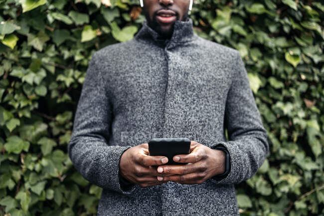 Perdere di un uomo d'affari afro controllare il suo telefono in città su uno sfondo verde — Foto stock