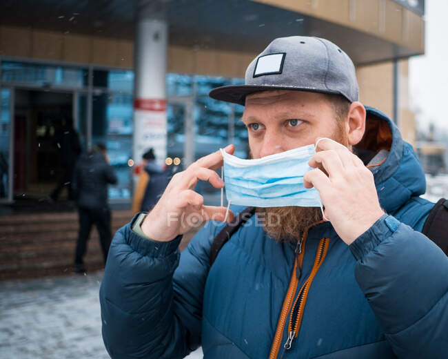 Man putting on face mask on a winter day — Stock Photo
