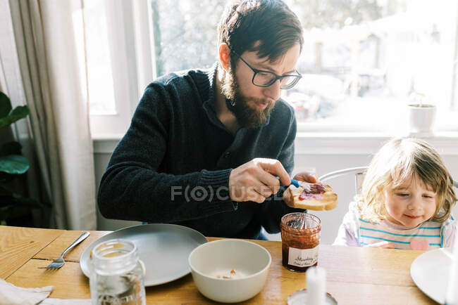 Uma família tomando café da manhã juntos na mesa de jantar em sua casa — Fotografia de Stock