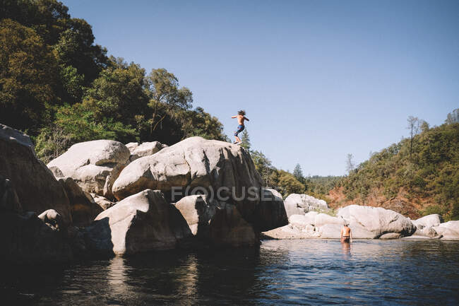 Ragazzo fa un salto Spin da un masso gigante in un locale Swimhole — Foto stock