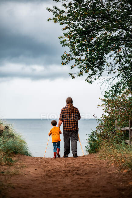 Un père et son fils marchant ensemble sur un chemin menant à la plage — Photo de stock