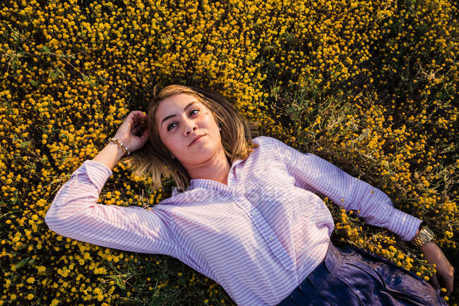 Mujer joven en el campo con flores posando - foto de stock