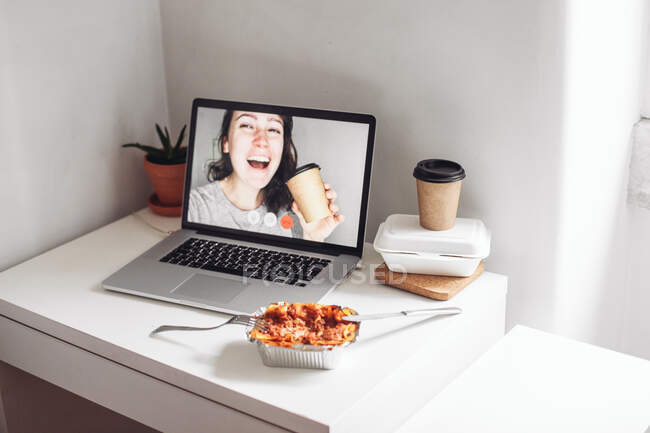 Видеозвонок с женщиной с чашкой на вынос, алюминиевая коробка с едой — стоковое фото