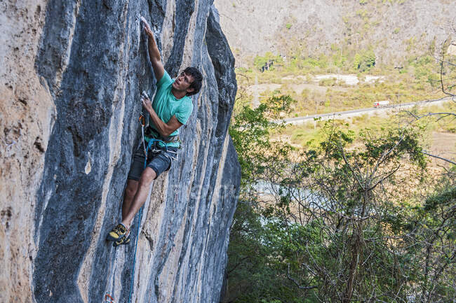 Чоловік піднімається на вапнякову скелю в Лаосі. — стокове фото
