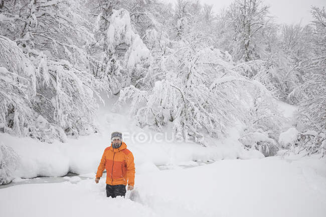 Uomo cercando di attraversare poco fiume nevoso — Foto stock