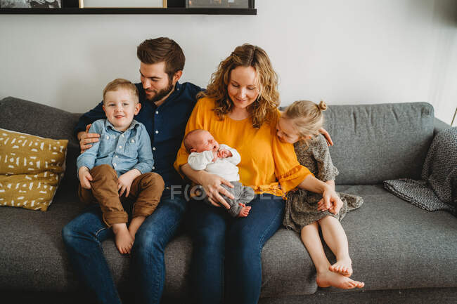 Família branca feliz com crianças pequenas e bebê sentado na sala de estar — Fotografia de Stock