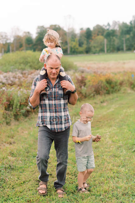 Grandfather and his grandchildren walking in a flowery meadow in MA — Stock Photo
