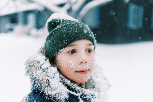 Niño pequeño lamiendo nieve de los labios durante la tormenta de nieve en Nueva Inglaterra - foto de stock