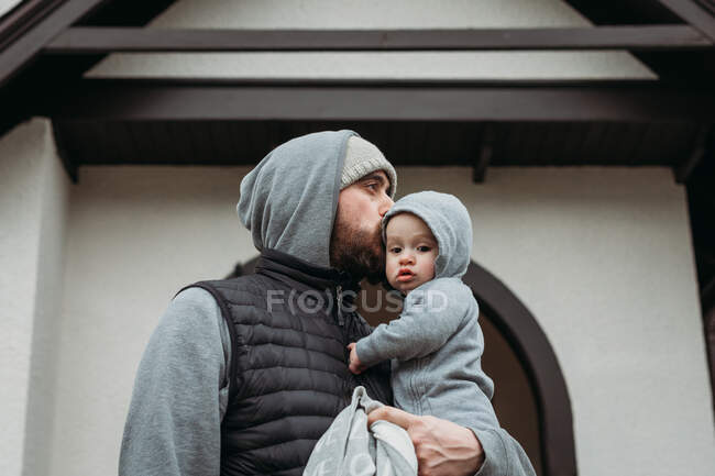 Allevamento padre baciare bambino il giorno freddo con cappuccio grigio corrispondenza — Foto stock