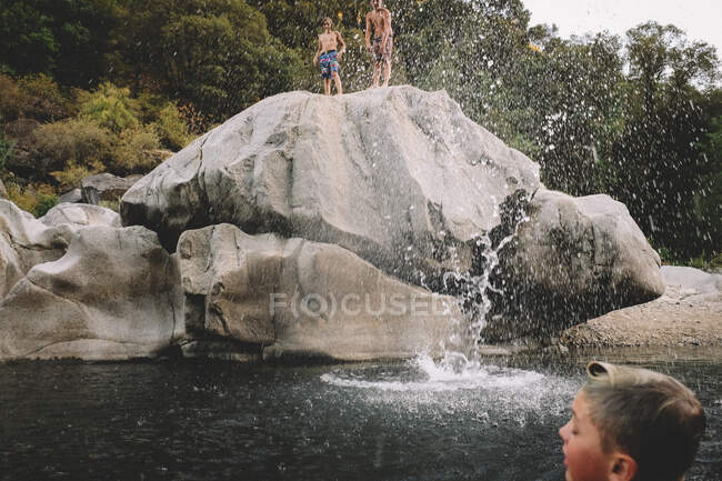 Freunde werden nach einem Sprung nass. Big Splash am Schwimmloch in der Dämmerung — Stockfoto