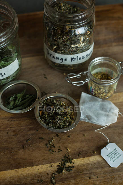 Puesta plana de hojas sueltas ingredientes de té de hierbas sobre un fondo de madera - foto de stock