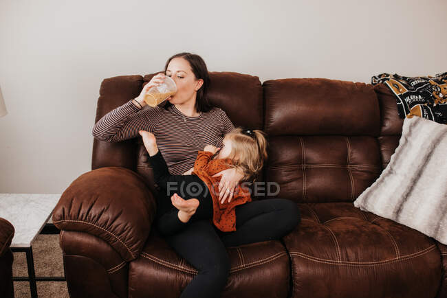 Belle jeune mère et sa fille sur canapé — Photo de stock