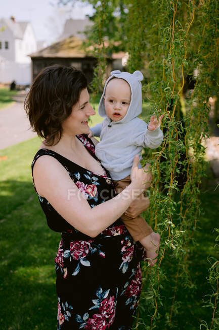 Mother and infant son smiling and playing in front yard in spring — Stock Photo