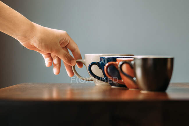 Hand holding a cup of cappuccino on a wooden table in a cafe or coffee shop — Stock Photo