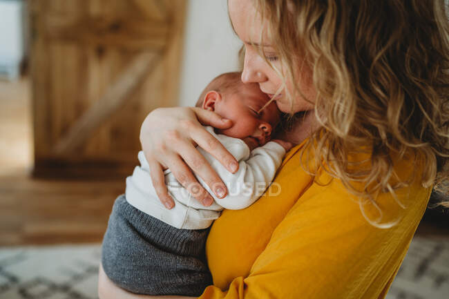Primo piano della bella mamma bionda che tiene in braccio il neonato — Foto stock