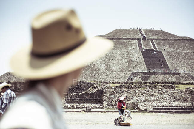 Sacred Mayan pyramid with Tourist in hat looking at street seller — Stock Photo