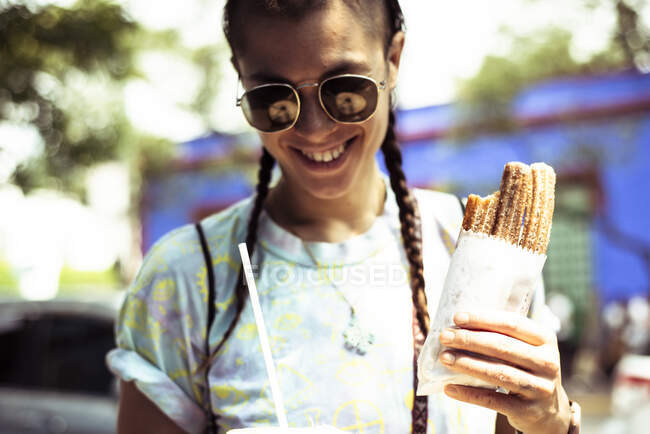 Sonriente hipster alternativo con churros fuera de Fridas House México - foto de stock