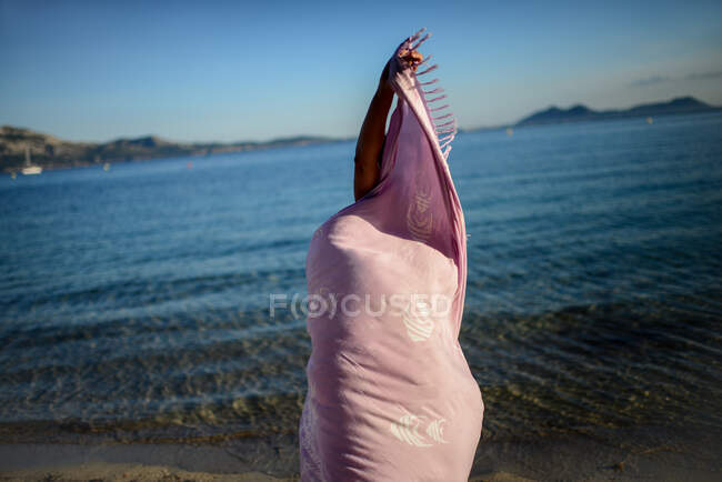 Young woman dances on the beach with sarong — Stock Photo