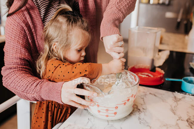 Beautiful young mother and her daughter cooking — Stock Photo