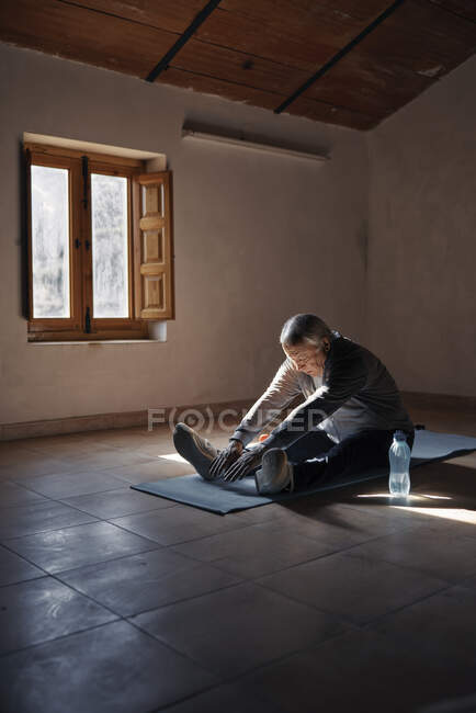 Пожилой человек делает упражнения на растяжку и тягу дома — стоковое фото