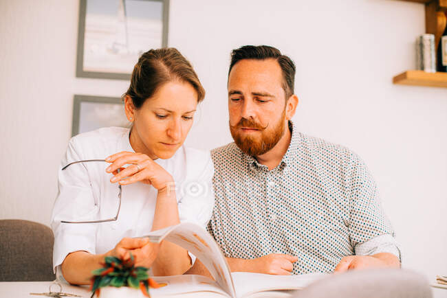 Мужчина и женщина читают книгу вместе с серьезным выражением лица — стоковое фото