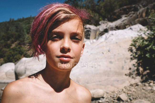 Мальчик с розовыми волосами и длинными ресницами смотрит в камеру — стоковое фото