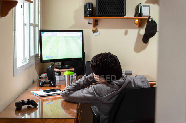 Gelangweilter Mann sitzt in seinem Zimmer und schaut sich ein Fußballspiel im Fernsehen an. — Stockfoto