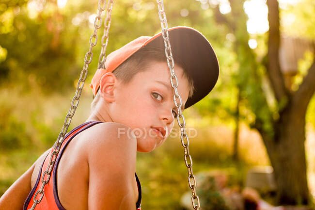 Pensativo adolescente en un columpio en verano - foto de stock