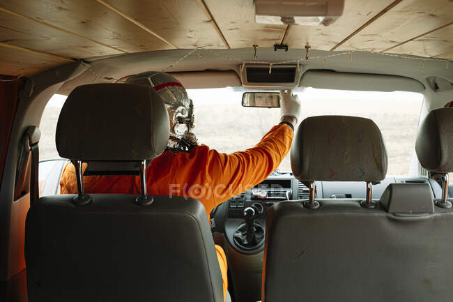 Человек, одетый как астронавт, кладет зеркало заднего вида фургона — стоковое фото