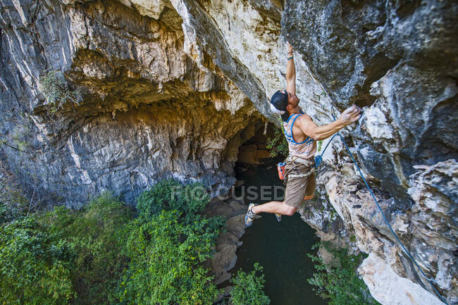 Человек, взбирающийся на известняковую скалу в Лаосе — стоковое фото