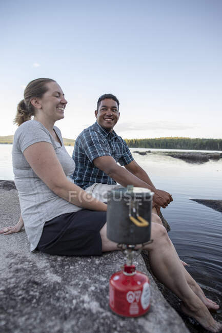 Africano uomo e donna bianca ridere e sorridere mentre campeggio con stufa — Foto stock