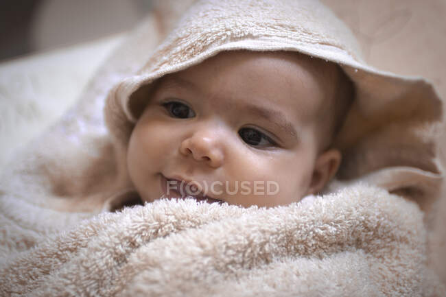 Ребенок катился в полотенце, оглядываясь и улыбаясь в ванной. — стоковое фото